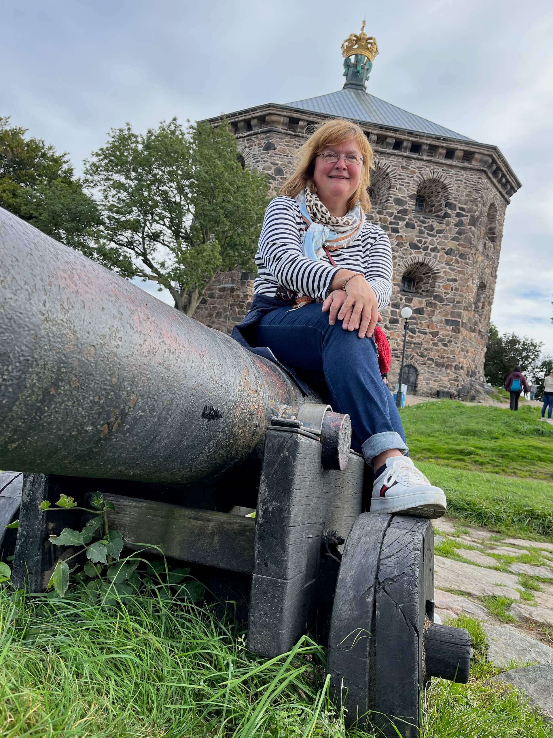 Sibille Kurdts sitzt auf einer alten Kanone und im Hintergrund eine schwedische Festung